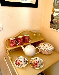 ein Regal mit Teetassen und Tellern darauf in der Unterkunft Le Jardin Enchanté in Giverny