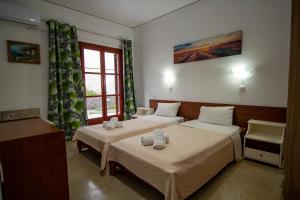 a hotel room with two beds and a window at Harrys bar & apartments in Acharavi