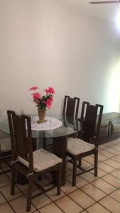 stół z krzesłami i wazon z kwiatami w obiekcie Apartamento confortável no centro de Guarapari w mieście Guarapari
