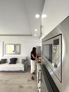 Una mujer parada en una habitación con un microondas. en Sunshine Luxury View Los Cristianos, en Los Cristianos