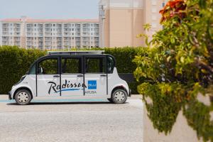 Radisson Blu Aruba في شاطئ بالم إيغل: سيارة بيضاء صغيرة متوقفة في موقف للسيارات