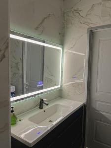 baño con lavabo y espejo grande en K7 Family 1комнатная квартира, en Atyraū