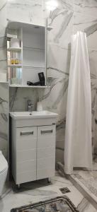 La salle de bains blanche est pourvue d'un lavabo et d'un miroir. dans l'établissement MiminoT&G, à Tbilissi