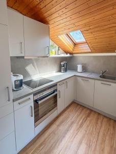 eine Küche mit weißen Schränken und einer Holzdecke in der Unterkunft Gästehaus Kayetan in Klais