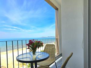 a table with flowers on a balcony with the beach at Sea Vista Apartment in Durrës