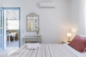 a white bedroom with a bed and a mirror at Aelia Apartment in Skopelos Town