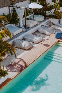 a pool with pillows and an umbrella next to a swimming pool at Nativo Hotel Ibiza in Santa Eularia des Riu