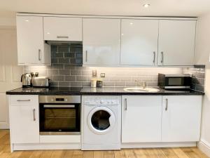 a kitchen with white cabinets and a washer and dryer at Prospect Apartment, 3 Guests, Free Parking & Wi-Fi in Reading