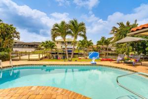 フォートマイヤーズにあるWaterfront Fort Myers Home Private Pool and Dockのヤシの木とリゾートのスイミングプール