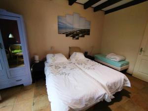 Un dormitorio con una cama blanca y una pintura en la pared en Gîte des Fours, en Agonges