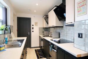 a kitchen with white counters and a sink at Breckfield House by Serviced Living Liverpool in Liverpool