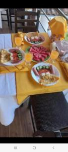 a table with plates of food and glasses of orange juice at Guest House Bumbli in Berat