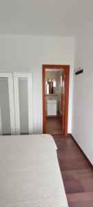 a bedroom with a white bed and a kitchen at Finca Rural La Casa Verde Shalom Tenerife in Las Lagunas