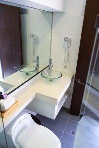 a bathroom with a sink and a mirror and a toilet at Hotel DC Feria in Bogotá