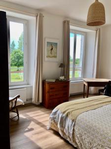 sypialnia z 2 oknami, łóżkiem i stołem w obiekcie La Maison du Hommeel w mieście Gratot
