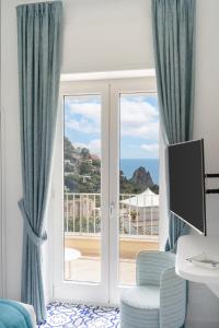 Casa Levante Luxury Apartments Capri في كابري: غرفة مع باب زجاجي منزلق مع إطلالة على المحيط