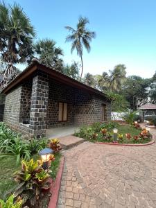 ein Backsteinhaus mit einem herrlichen Garten davor in der Unterkunft Tattvamasi Retreat in Mumbai