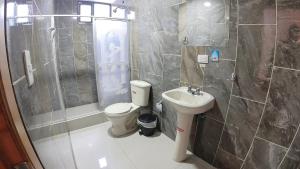 a bathroom with a shower and a toilet and a sink at Hostal Flor de los Ángeles in Guamote