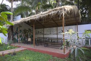 un bâtiment avec des bancs et un toit de chaume dans l'établissement Tattvamasi Retreat, à Mumbai