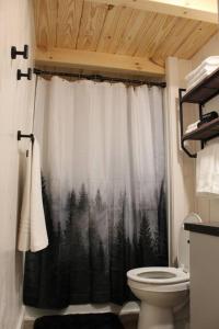 baño con aseo y cortina de ducha con árboles en The Bellefonte Campground en Bellefonte