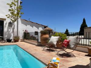 einen Pool mit zwei Stühlen neben einem Haus in der Unterkunft Stunning Spanish white village home Private pool Stunning Views in Saleres