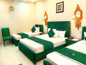 a hotel room with three beds and a chair at Golden One Hotel in Lahore