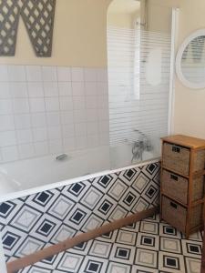 a bathroom with a tub and a tile floor at Brittany France 2 Beds Free Wi-Fi - Parking & Garden in La Haye