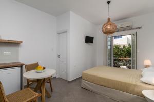 a bedroom with a bed and a table and a kitchen at Studios Kymata in Pollonia