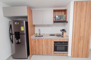 een keuken met een roestvrijstalen koelkast en houten kasten bij Hermoso Apartamento tipo Loft en Rodadero Santa Marta in Santa Marta