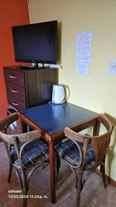 a wooden table with two chairs and a television at Mirador del Beagle Hosteria in Ushuaia