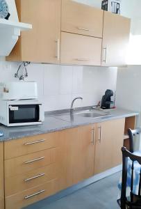 a kitchen with a sink and a microwave at 3 bedrooms apartement with city view shared pool and enclosed garden at Feijo 5 km away from the beach in Almada