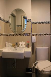 een badkamer met een wastafel, een toilet en een spiegel bij โรงแรมวีวิช V Wish Hotel in Khon Kaen