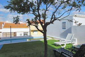 a white chair sitting next to a tree in a yard at 2 bedrooms apartement with shared pool enclosed garden and wifi at Almada 5 km away from the beach in Almada