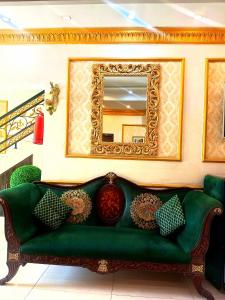 a green couch in a room with a mirror at Golden One Hotel in Lahore