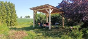 a wooden pergola with a table and chairs in a field at Apasjonata in Świdnica