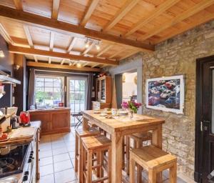 uma cozinha com uma mesa de madeira e uma parede de pedra em Maison et son jardin situés dans le Condroz em Marchin