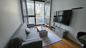 uma sala de estar com um sofá e uma televisão de ecrã plano em Ruby room - 20 min to Paris em Créteil
