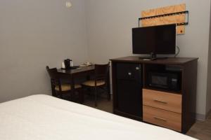 Habitación de hotel con cama, TV y mesa. en University Manor Inn, en Buffalo