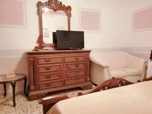 een slaapkamer met een dressoir met een spiegel en een stoel bij 2 bedrooms apartement at Agrigento 700 m away from the beach with sea view enclosed garden and wifi in Agrigento