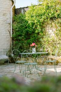 una mesa y sillas con un jarrón de flores. en Les Glycines de Monchy- Chambres d'hôtes, en Monchy-Humières