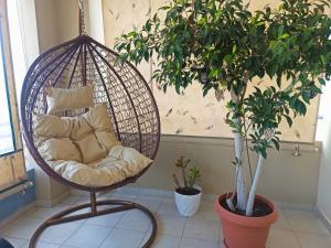 a hanging chair with pillows in a room with two plants at Nefeli's Home- Family luxury apartment in Heraklio Town