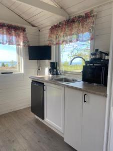 uma cozinha com armários brancos, um lavatório e uma janela em Stuga vättervy em Gränna