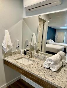 baño con lavabo, espejo y cama en Lakeside Motel, Cabins and RV en Kingston