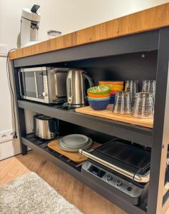 a kitchen shelf with dishes and a microwave at Luxury studio with balcony in Reykjavík