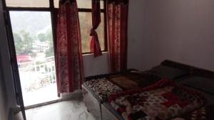 a bedroom with a bed in front of a window at hotel holy spirit, sitapur in Sonprayag +3 photos