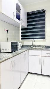 a white kitchen with a microwave and a sink at blueocean.cog Apartments in Benin City