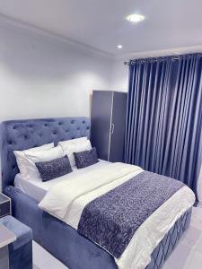 1 dormitorio con 1 cama azul y 2 almohadas en blueocean.cog Apartments, en Benin City