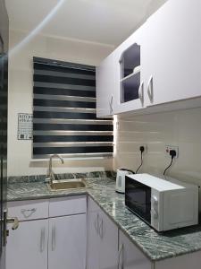 a kitchen with white cabinets and a microwave on a counter at blueocean.cog Apartments in Benin City