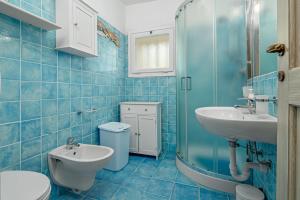 un bagno piastrellato blu con lavandino e WC di Il suono del mare a Porto Cervo Altre 35 foto