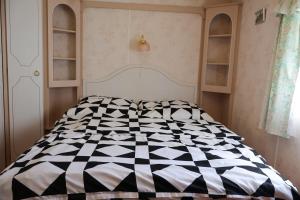 a bedroom with a black and white comforter on a bed at Domki na Ogrodowej in Trzęsacz